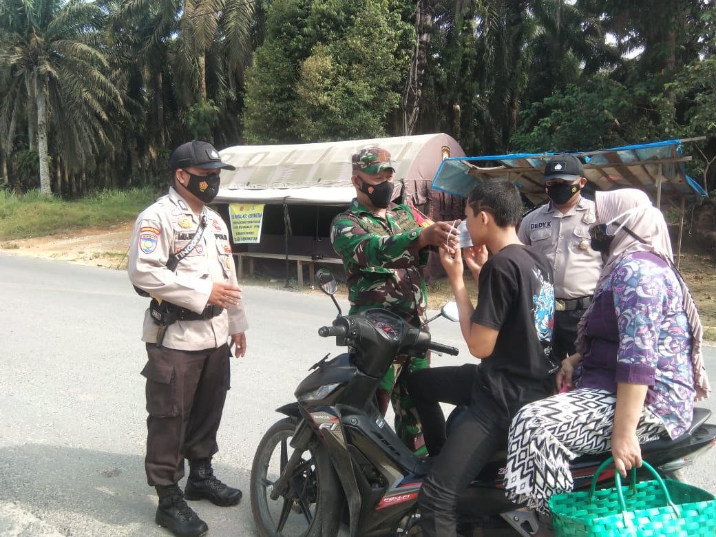Bhabinkamtibmas Polsek Kerumutan Himbau Warga dan Bagikan masker di Pos PPKM